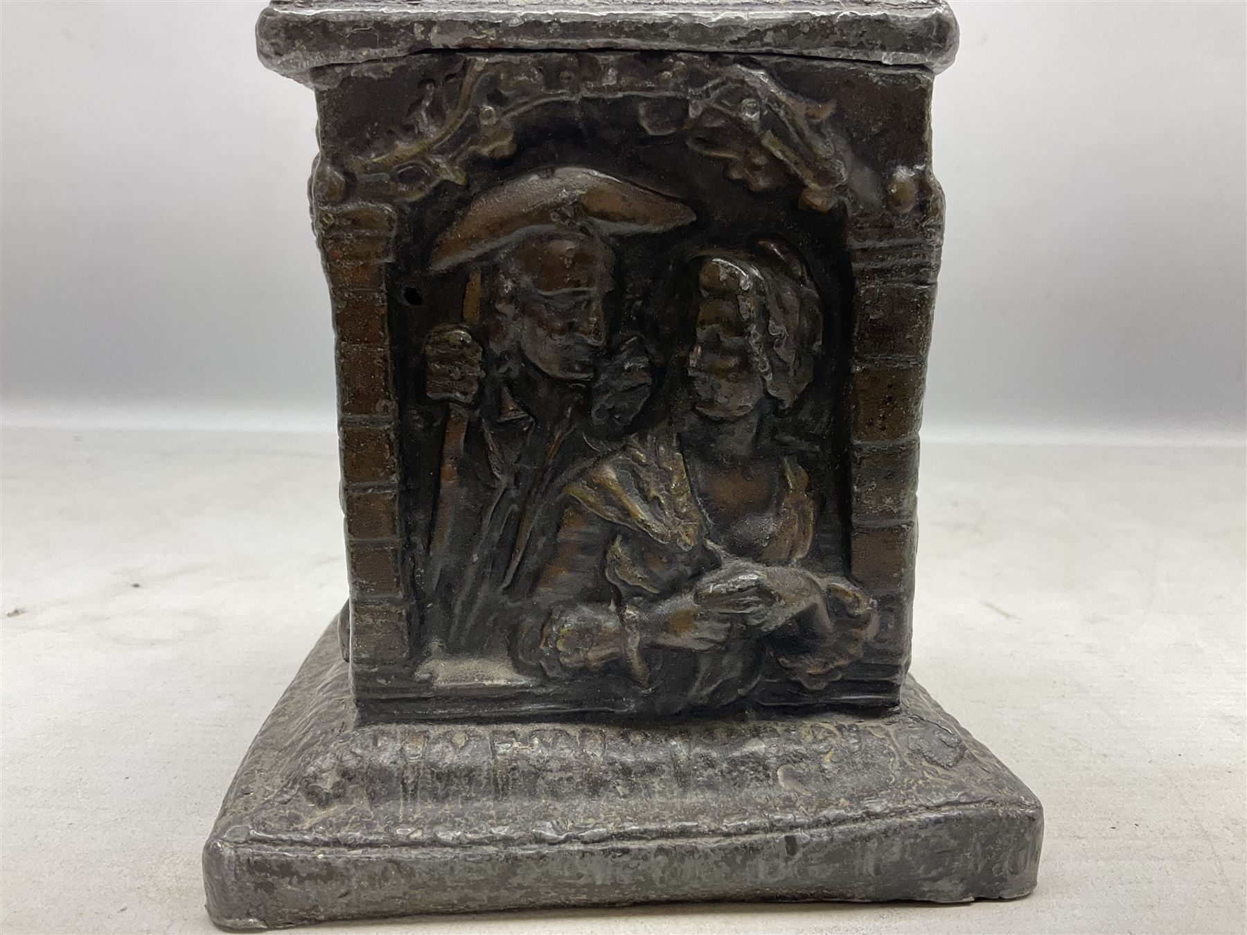 19th century lead tobacco box, the body of square form decorated with panels of courting couples in relief supporting stepped tapering lid with figural male head finial, H18.5cm