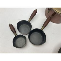 Four Victorian copper moulds, together with a graduating set of copper pans with wooden handles and finials to covers, largest pan 