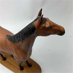 A Bewick figurine, modelled as a chestnut horse, Red Rum, raised upon an oval wooden base with plaque detailed ‘Red Rum Winner of The Aintree Grand National 1973, 1974 and 1977, The Scottish Grand National 1974’, including base H31.5cm. 