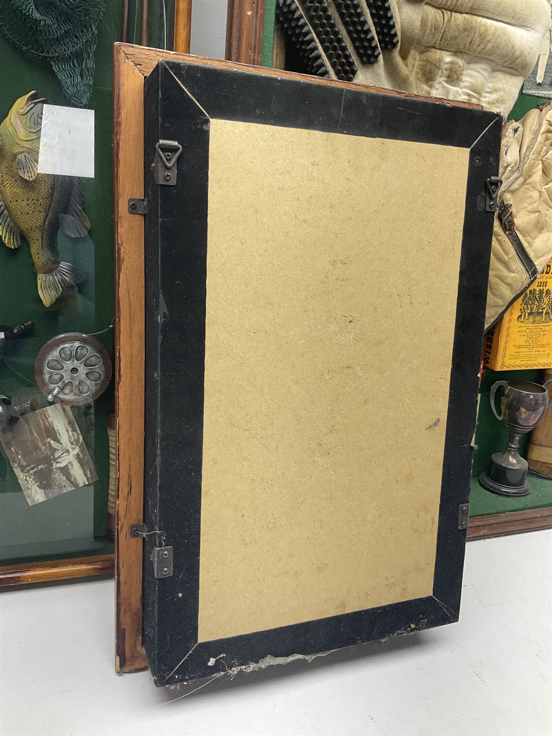 Four framed sporting memorabilia displays, the largest example containing 1930s cricket memorabilia, together with two fishing displays and a football display, each within wooden glazed frames, largest H105cm