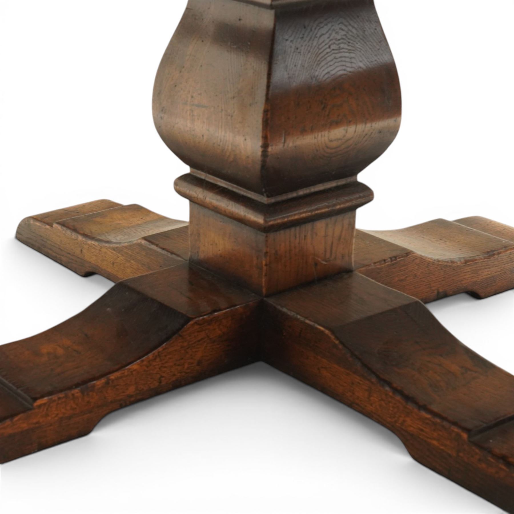 Early 20th century oak centre table, the large circular top raised on a squared and turned baluster pedestal, terminating to four splayed supports