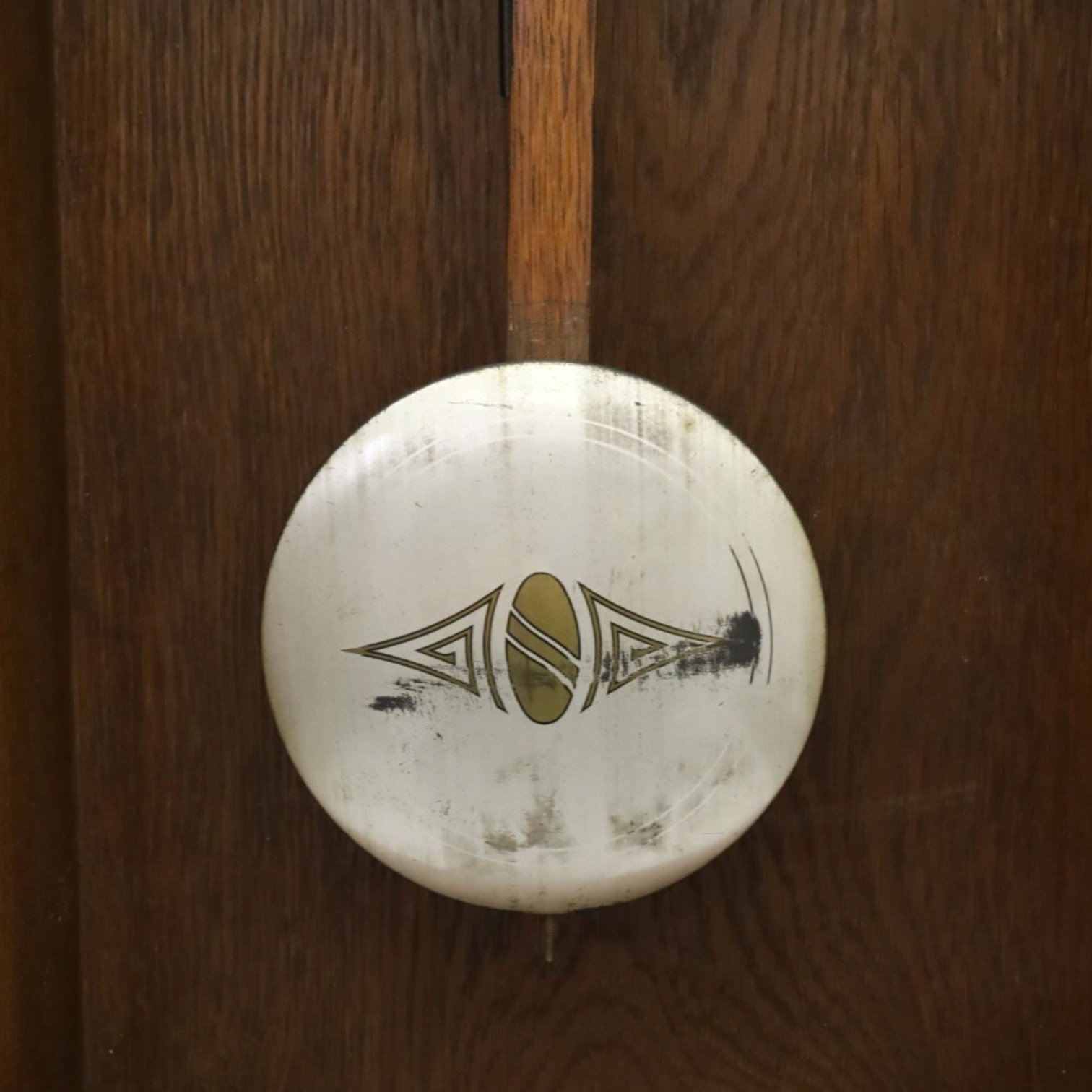 Art Deco style oak wall clock, moulded cornice above a silvered dial with Arabic numerals and geometric spandrels, glazed door with geometric bevelled glass panels enclosing a circular pendulum, on a stepped moulded base