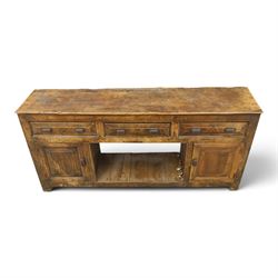 18th century rustic oak dresser base, with fielded panels and iron cup handles with embossed greek key and foliate detail, three short drawers above and open recess flanked by two cupboard doors, raised on stile supports