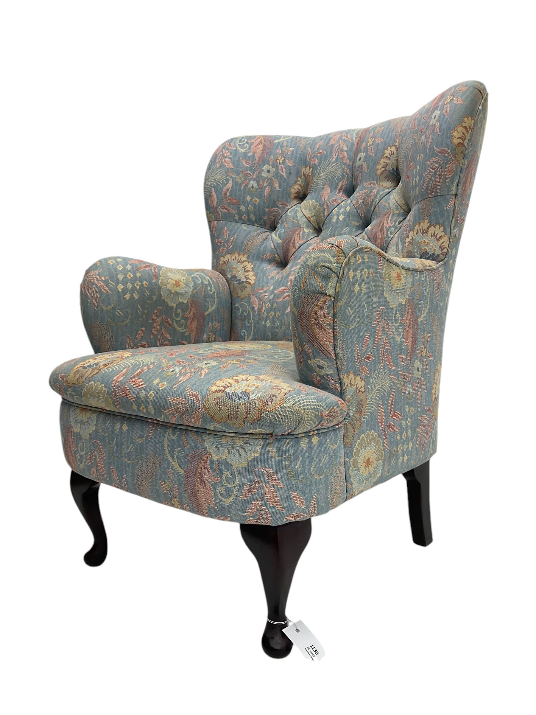 Mid-20th century wingback armchair, upholstered in soft blue floral patterned fabric with button-tufted backrest and curved arms and raised on cabriole supports