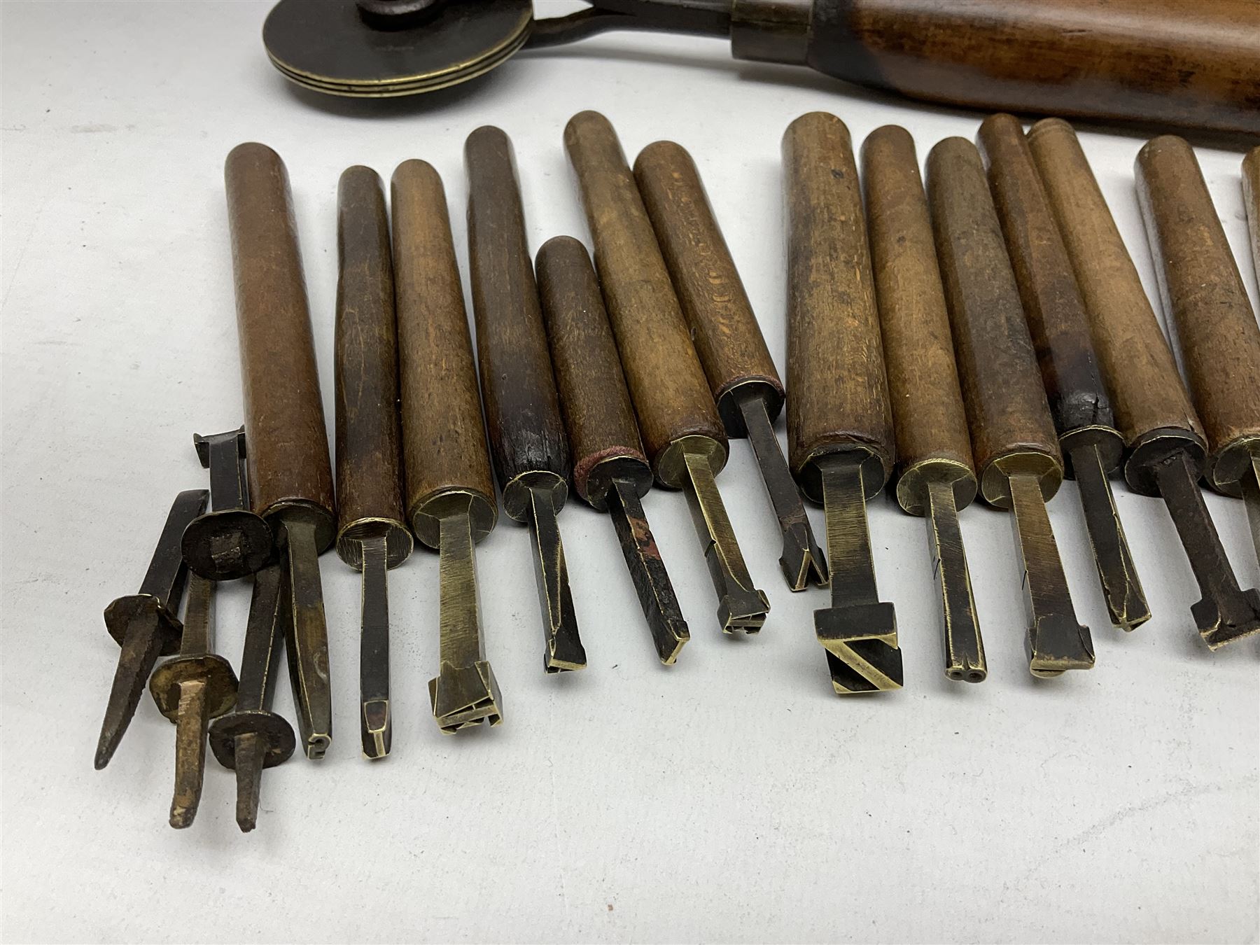 Thirty-one bookbinder's brass number and letter stamps, predominantly with beech handles, together with a bookbinder' decorative fillet roll, with brass triple line wheel stamped E. Menuel London, with wood handle, and two ink blotters