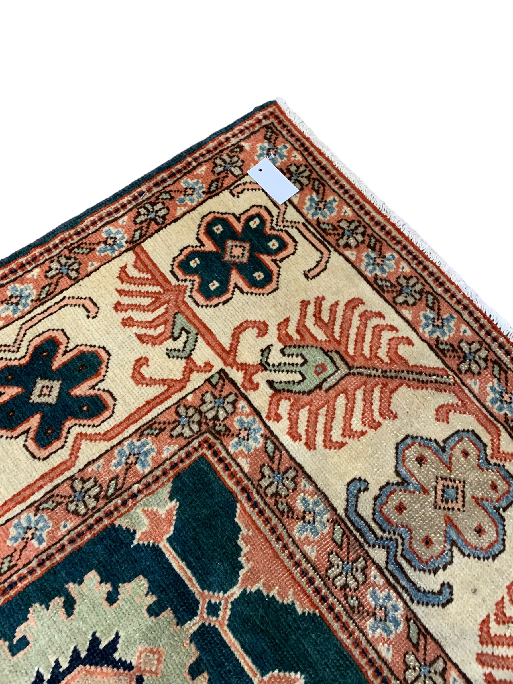 Persian emerald green ground rug, the field decorated with large stylised plant motifs, ivory ground border with repeating leaf motifs, the guards decorated with trailing branch and flowerhead motifs