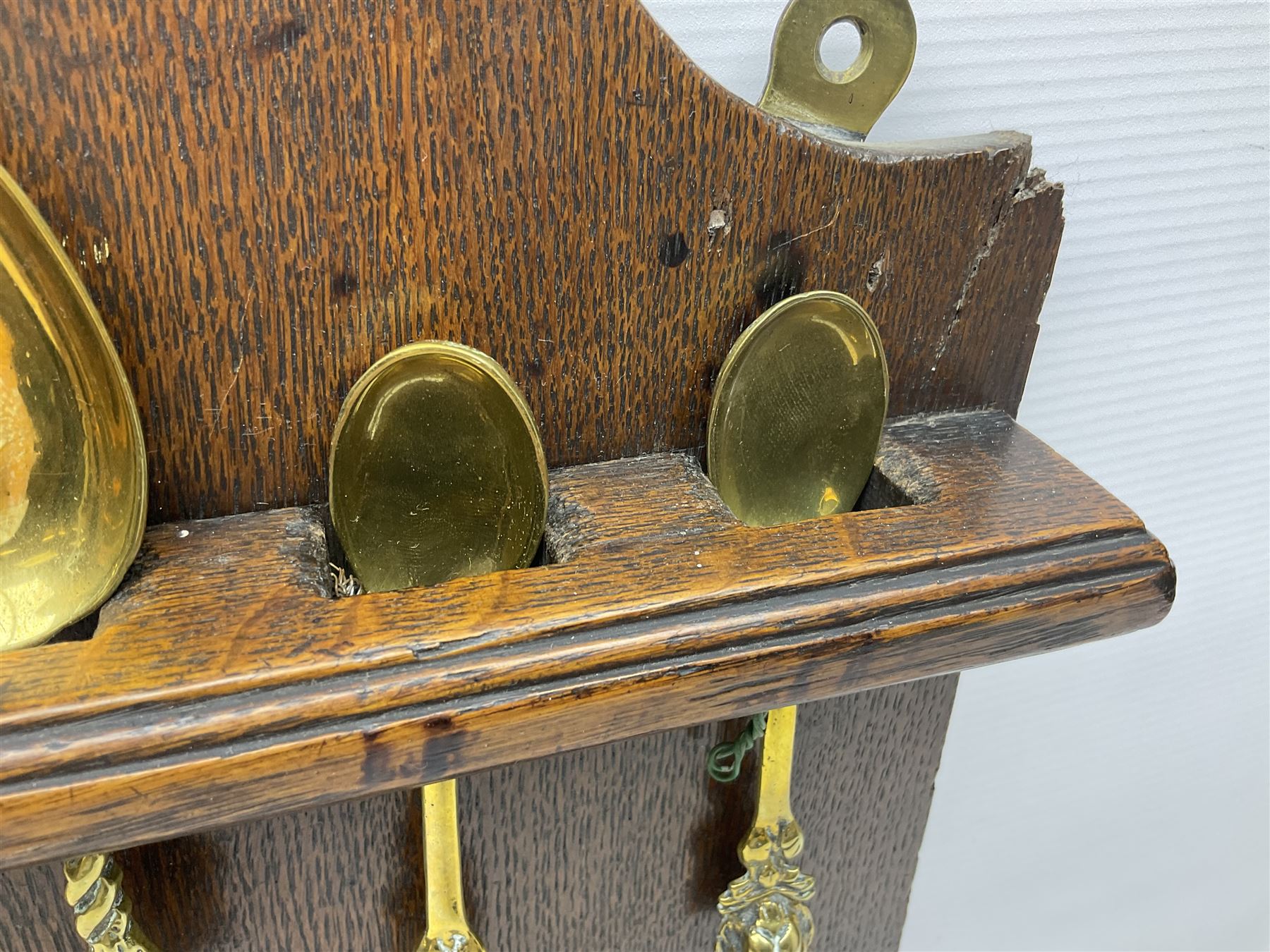 George III oak spoon rack and candle box, the rectangular backplate with shaped  pediment and two six aperture spoon racks, above a candlebox with hinged cover, with various brass spoons and a pair of brass candle snuffers, H56.5cm, W35cm, D14cm 