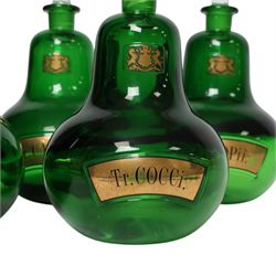 Set of four 20th century Royal Pharmaceutical Society green glass bottles, of bellied form with clear cut glass spire stopper, each body bearing gilt label in Latin: Tr.OPii., Tr.COCCi., Tr.CANNAB., and Tr.LOBEL., and gilt Royal Pharmaceutical Society crest to neck, H25cm

Provenance: From the collection of the family of Peter Green, a practising pharmacist whose career spanned the mid to late 20th century. During his professional life he managed pharmacies in Yeovil, Somerset, and later Selles Chemist in Filey, North Yorkshire, before purchasing and running his own business, Peter Green Pharmacy, located in the Market Place, Malton. The bottles were displayed as part of the traditional shop fittings in both the Filey and Malton pharmacies and were retained as part of his collection.