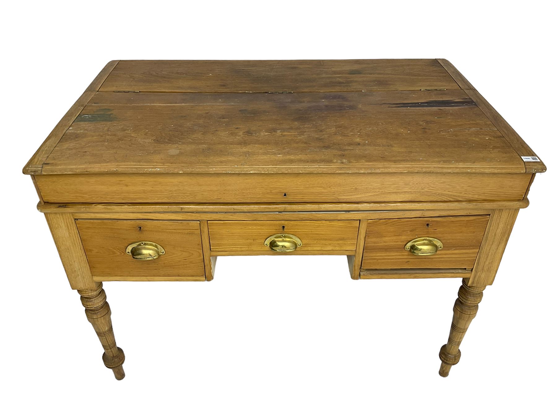 Early 20th century light oak kneehole desk, rectangular hinged top, fitted with frieze drawer flanked by two deep drawers, raised on ring turned supports