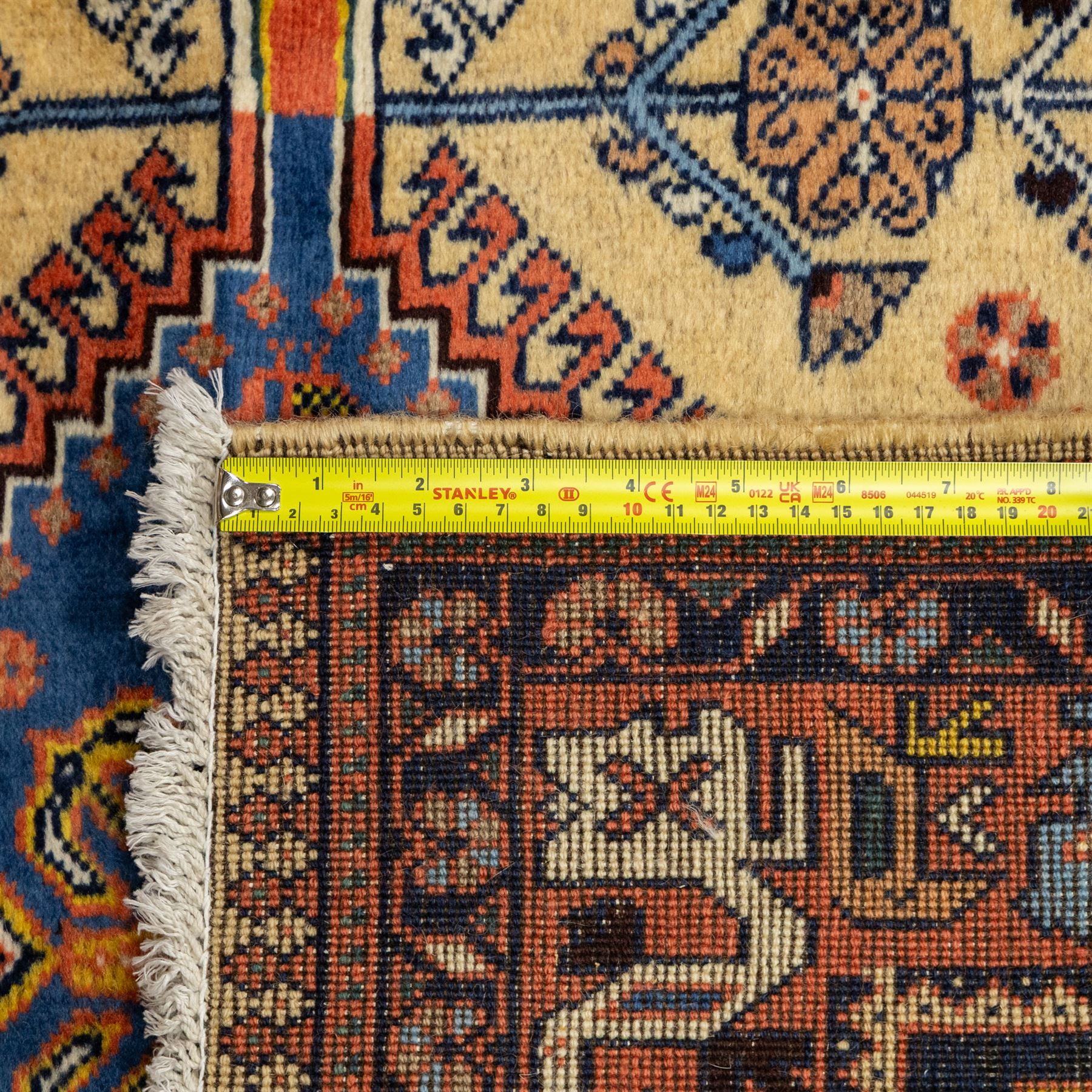 South Persian Yallameh hand-knotted rug, ivory ground, with a central stepped pole medallion design in blue and terracotta tones, surrounded by geometric tribal motifs incorporating stylised flowerheads, birds, hooked devices and angular vine work, enclosed by dark navy spandrels and a terracotta border with repeating geometric motifs, flanked by narrow patterned guard stripes, with cotton fringes