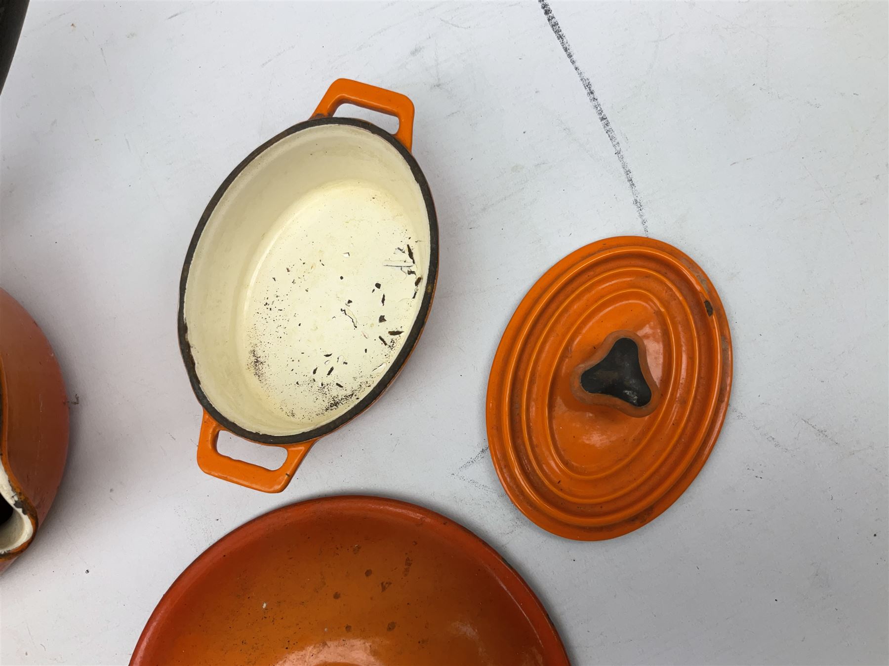 Le Creuset 'Volcanic Orange' cast iron and enamel saucepans and two lidded casserole dishes  