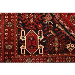 Persian tribal hand-knotted rug, crimson ground, madder field with central stepped lozenge medallion with scattered floral and geometric spandrels with rosette border 
