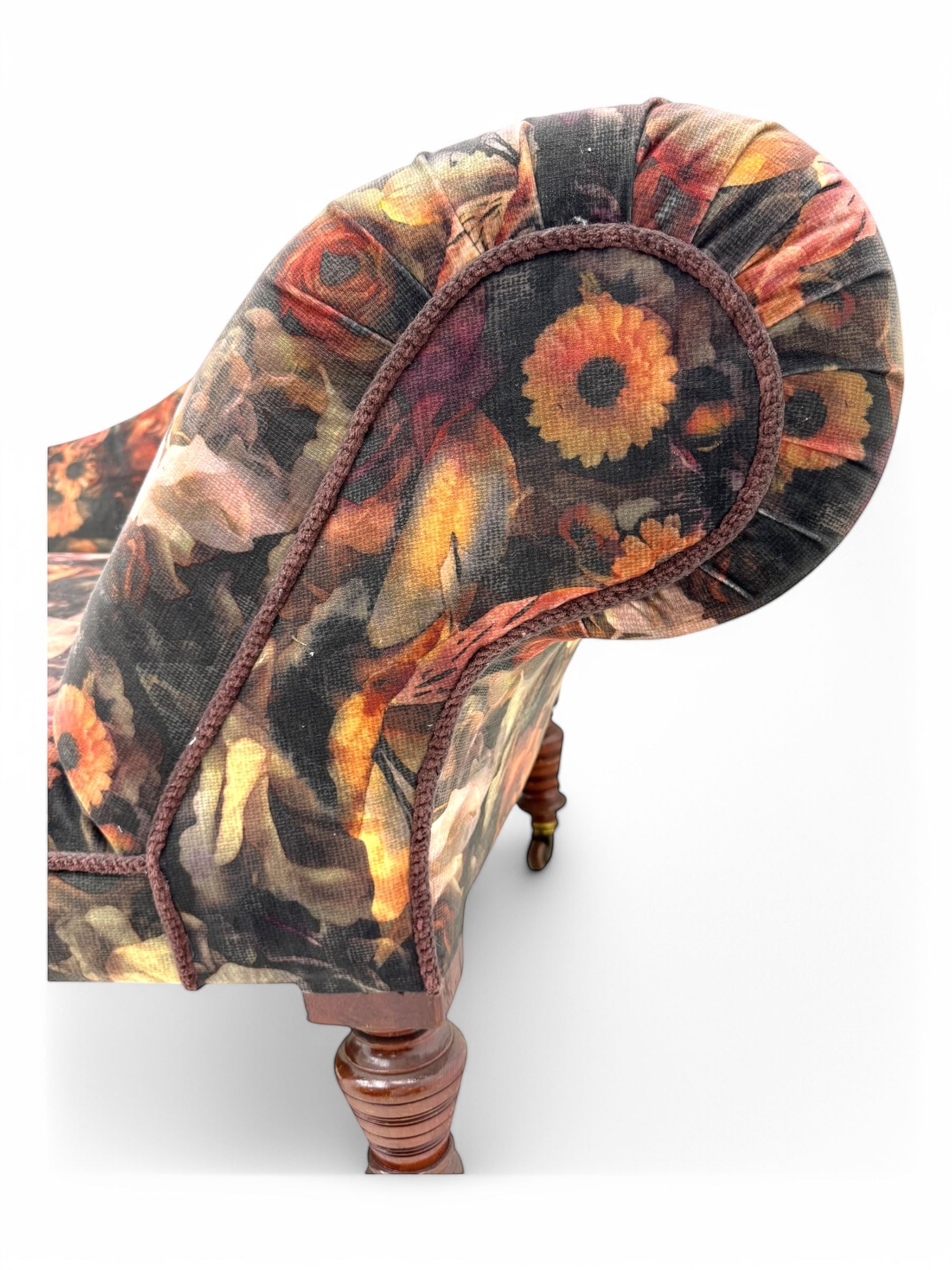 Victorian hardwood-framed chaise longue, serpentine back with rolled arm, upholstered in floral pattern fabric, on ring turned legs with ceramic castors 