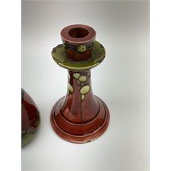 Minton Secessionist vase, with tube-lined stylised flower head decoration upon a red and green ground, printed mark to base 'Minton Ltd, No. 31', together with a matching pair of Minton Secessionist candle sticks, candlestick H17cm