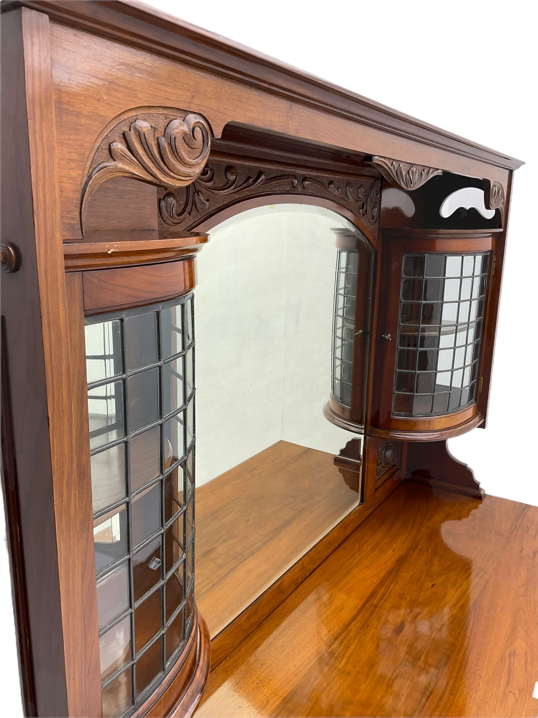 Late Victorian walnut mirror back sideboard or dresser, the raised back fitted with two curved and lead glazed cabinets, central arched bevelled mirror, the sideboard with break bowfront, fitted with six drawers and two cupboards, the cupboard doors panelled and carved with scrolls, shell and plant motifs, shaped apron with cabriole feet
