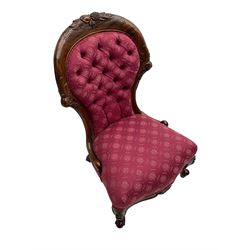 Victorian style mahogany framed nursing chair, the cresting rail carved with fruit and foliage, upholstered in red patterned fabric with buttoned back, on cabriole supports with scrolled terminals