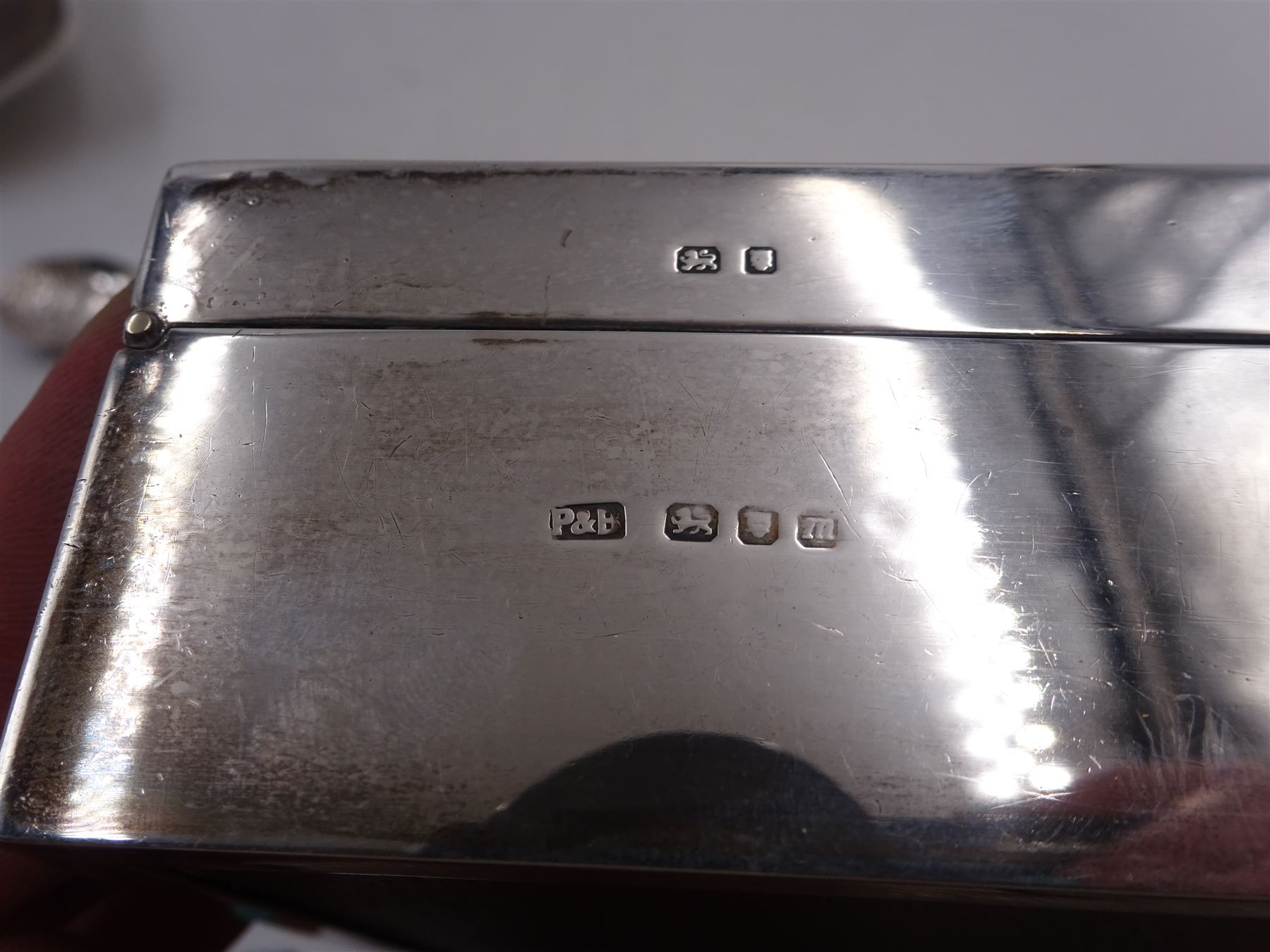 Modern silver mounted cigarette box, of plain rectangular form, with personal engraving to hinged cover, opening to reveal soft wood lined interior, H3.8cm, W21.5cm, hallmarked Padgett & Braham Ltd, London 1967, together with a silver cigarette case, with engraved C scroll decoration, hallmarked Joseph Gloster Ltd, Birmingham 1917 or 1942 and a silver souvenir spoon