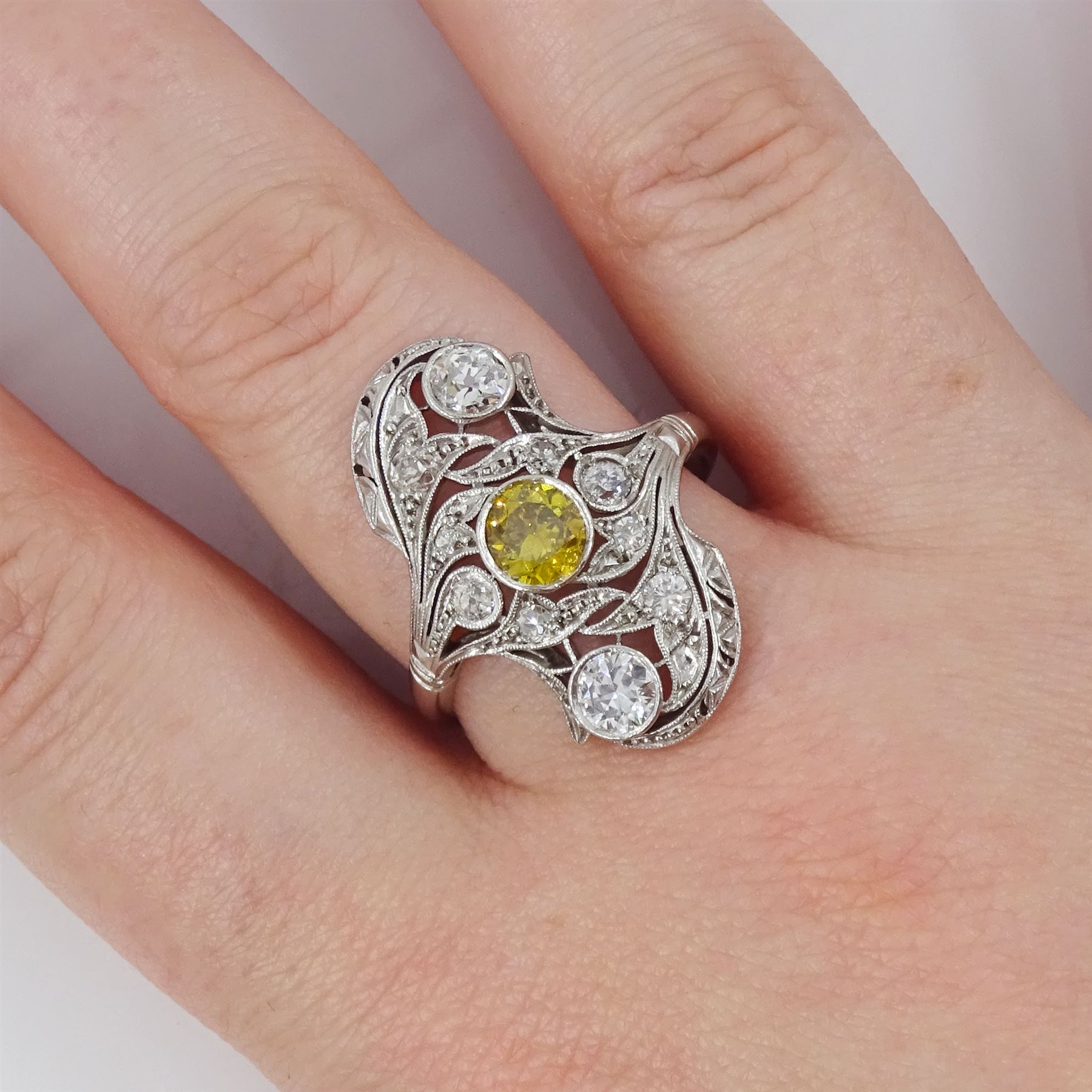 Early 20th century platinum diamond swirl ring, the principal old cut fancy yellow diamond of approx 0.50 carat, surrounded by old cut and single cut diamonds, in a milgrain pierced foliate design setting, total diamond weight approx 1.25 carat, with GCS certificate