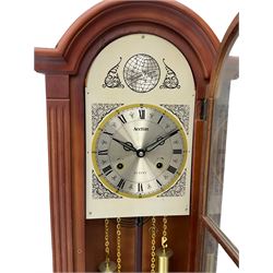 A contemporary Acctim (Anglo continental clock company) thirty-one day striking wall clock in a mahogany effect case with a fully glazed door displaying the pendulum and two dummy wights with chains, with a polished brass dial, Roman numerals, minute track and pierced steel hands, dial plate decorated with spandrels and Tempus Fugit inscribed on the dial brake-arch.
With key and pendulum.

