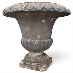 Set of three 19th century weathered carved sandstone garden urns of Neoclassical campana form, the broad everted rim carved with pointed egg-and-dart motifs, above a plain waisted bowl with gadrooned underbelly, on moulded rope-twist socle and square plinth base