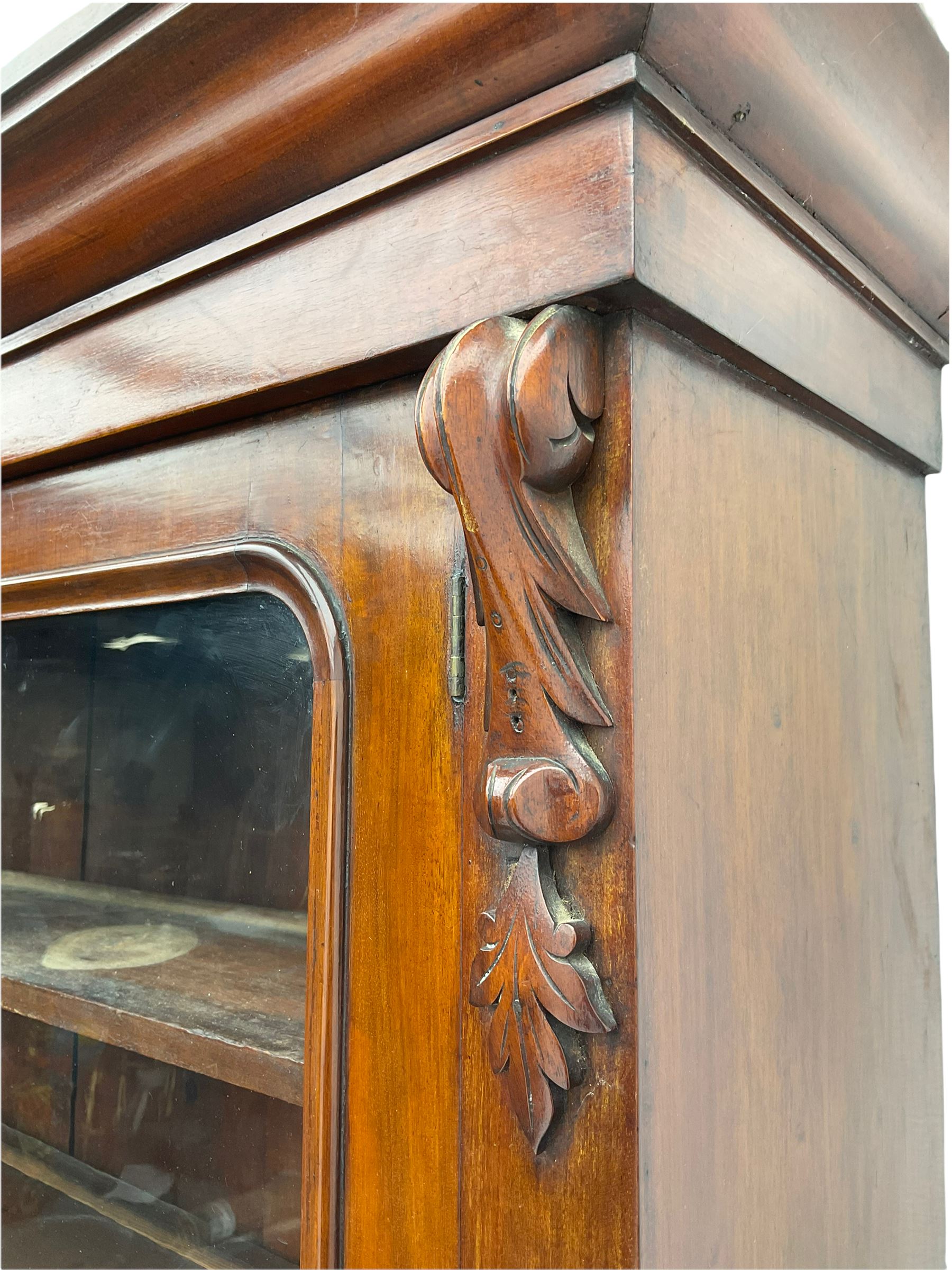 Victorian mahogany bookcase on cupboard, projecting cornice over two glazed doors and carved corbels, fitted with two drawers and double cupboard, plinth base