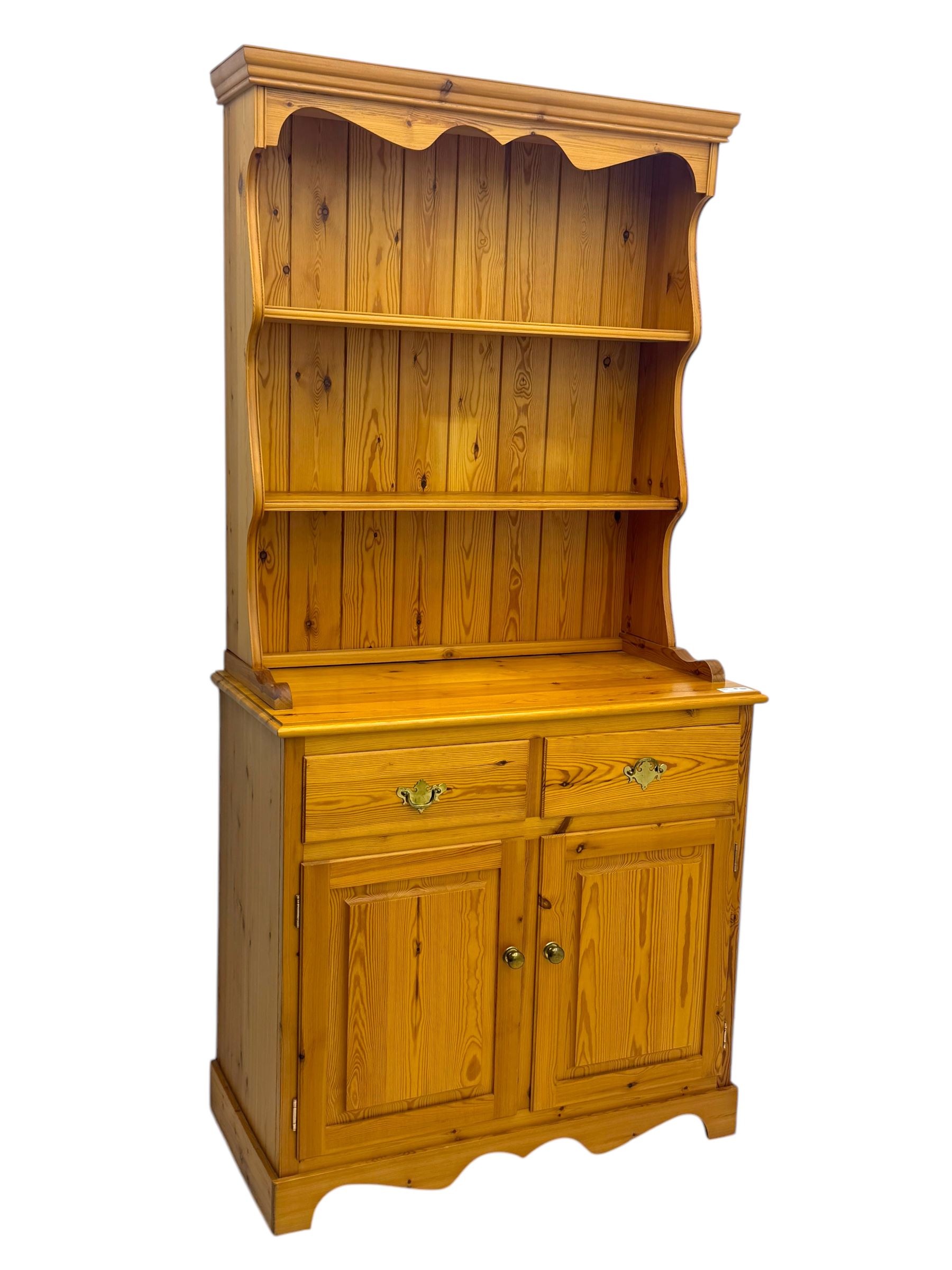 Victorian design pine dresser, projecting moulded cornice over scalloped frieze and two open shelves, base fitted with two drawers over double cupboard, on shaped plinth base