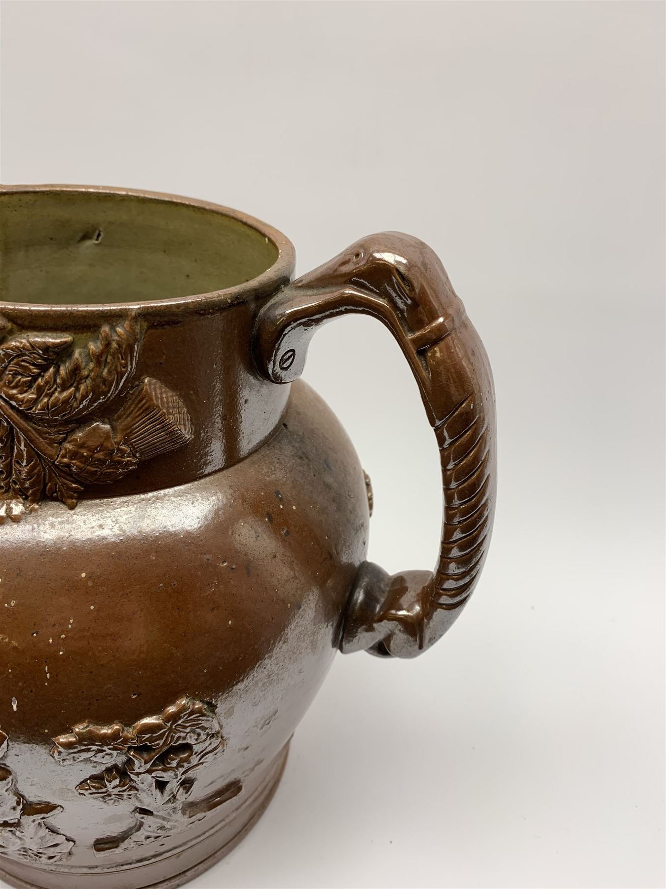 19th century salt glazed stoneware jug, with mask spout and greyhound modelled handle, the body decorated in relief with Royal Coat of Arms flanked by lions, the rim with the flowers of the union, roses, thistles and shamrocks, H26.5cm
