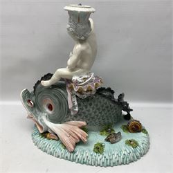 Early 20th century continental centrepiece, modelled as a putti riding a dolphin, upon a blue base decorated in relief with seaweed, flowers and shells, with spurious mark beneath