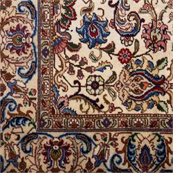 North West Persian Tabriz, hand-knotted carpet, ivory ground with dense scrolling vine-work, palmettes, flowering sprays, and stylized leaves framed by a principal border of scrolling floral motifs and palmettes and flanked by narrow guard borders, with cotton fringe ends
