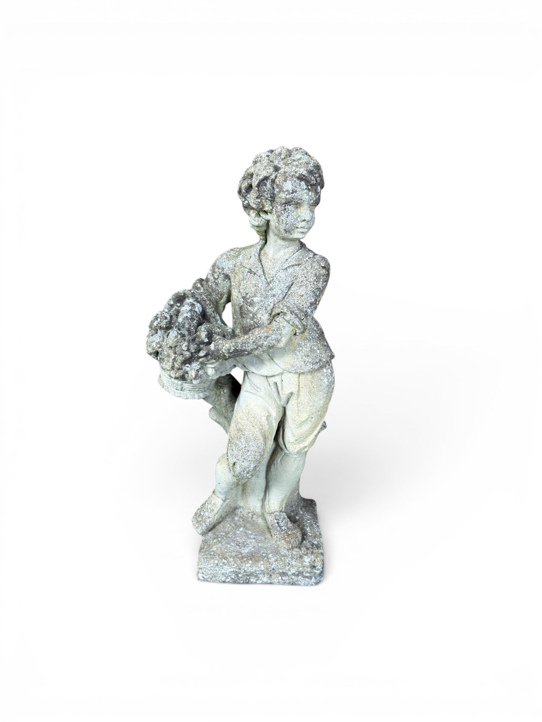 Weathered cast stone garden figure depicting a child holding a fruit basket