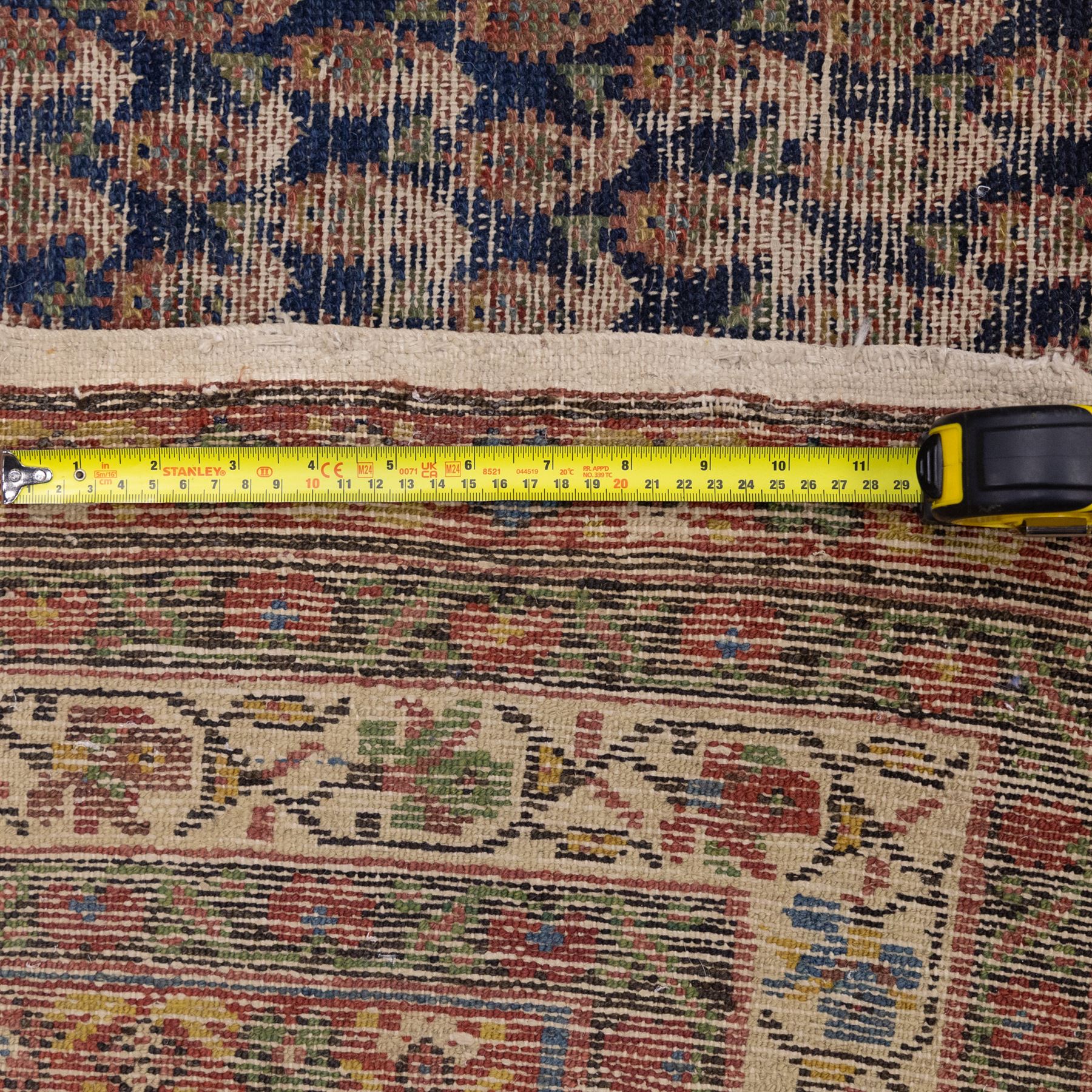 West Persian Kurdish vintage carpet, indigo field decorated with an all-over repeating boteh design arranged in diagonal rows framed by angular spandrels and enclosed by multiple geometric borders in a palette of indigo blue, madder red, soft green and ivory