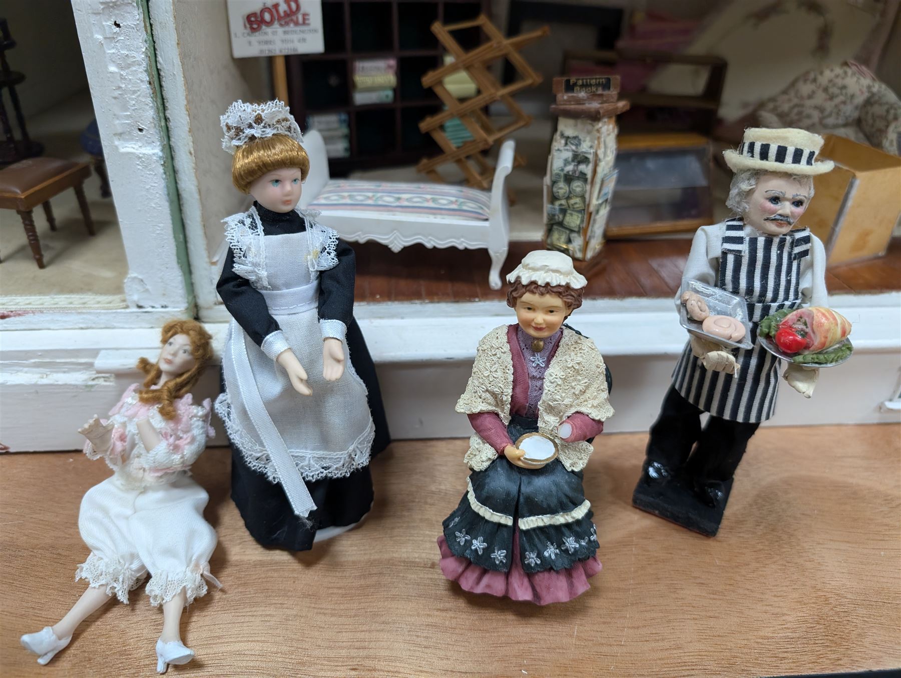 Two modern three storey dolls houses, each painted green with decorated interiors, both upon a single white wooden base, together with a large collection of dolls house furniture, accessories and figures 