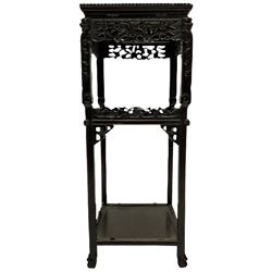 Early 20th century Oriental hardwood plant stand, the square top with bead moulded edge, two undertiers joined by supports carved with dragon masks and foliage, the frieze and raised panels carved and pierced with flower heads and foliate