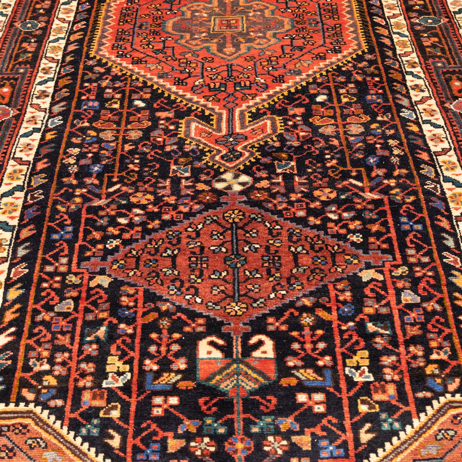 North West Persian Koliahee hand-knotted runner, indigo field with three large linked lozenge medallions in a madder red, framed by angular floral motifs and stylized vines within ivory and terracotta geometric borders, fringe ends  