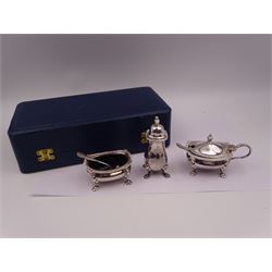 Modern silver three piece cruet set, comprising pepper shaker, open salt and mustard pot with cover, each with oblique gadrooned rim, palmette corners and upon four paw feet, with two matching spoons, hallmarked William Suckling Ltd, Birmingham 1992, the mustard pot and salt with blue glass liners, all contained within tooled leather silk and velvet lined fitted case, stamped Harrods London to interior silk lining