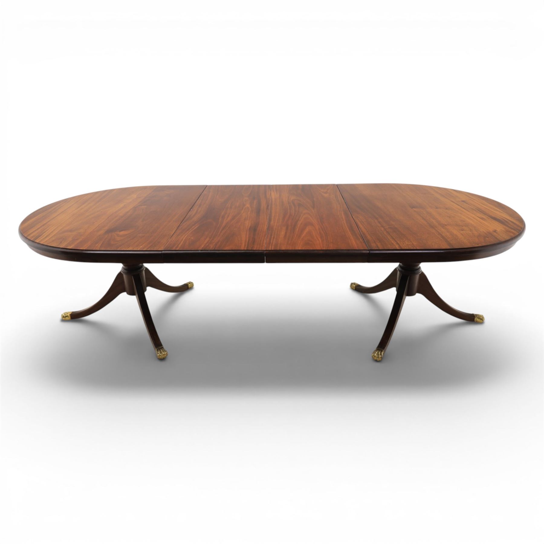 Regency design mahogany extending twin pedestal dining table with two additional leaves, raised on splayed supports terminating brass paw feet
Extends to 268cm