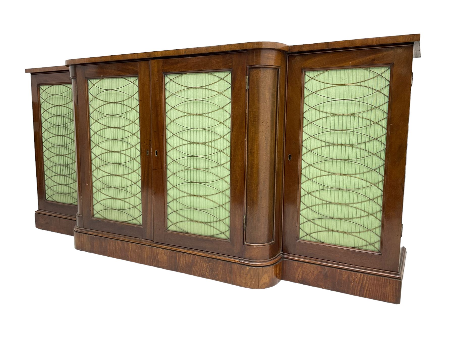 19th century mahogany break-front sideboard, raised brass gallery back with Greek key design, fitted with four cupboard doors, their pleated green fabric overlain with gilt metal grilles, lower moulded edge over plinth base