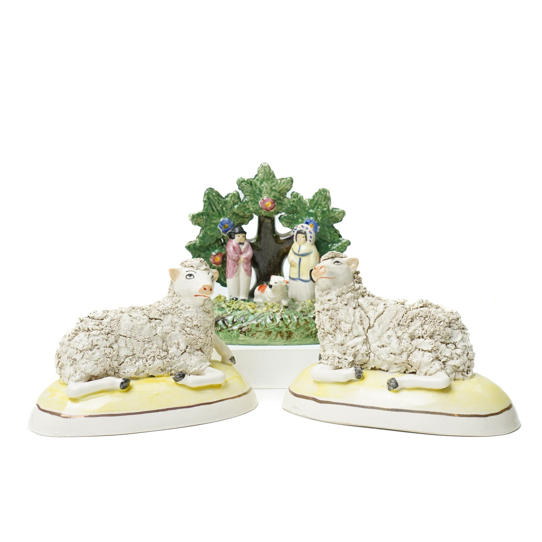 Pair of 19th century Staffordshire sheep, W13cm; together with a pearlware bocage group, H12cm (3)
