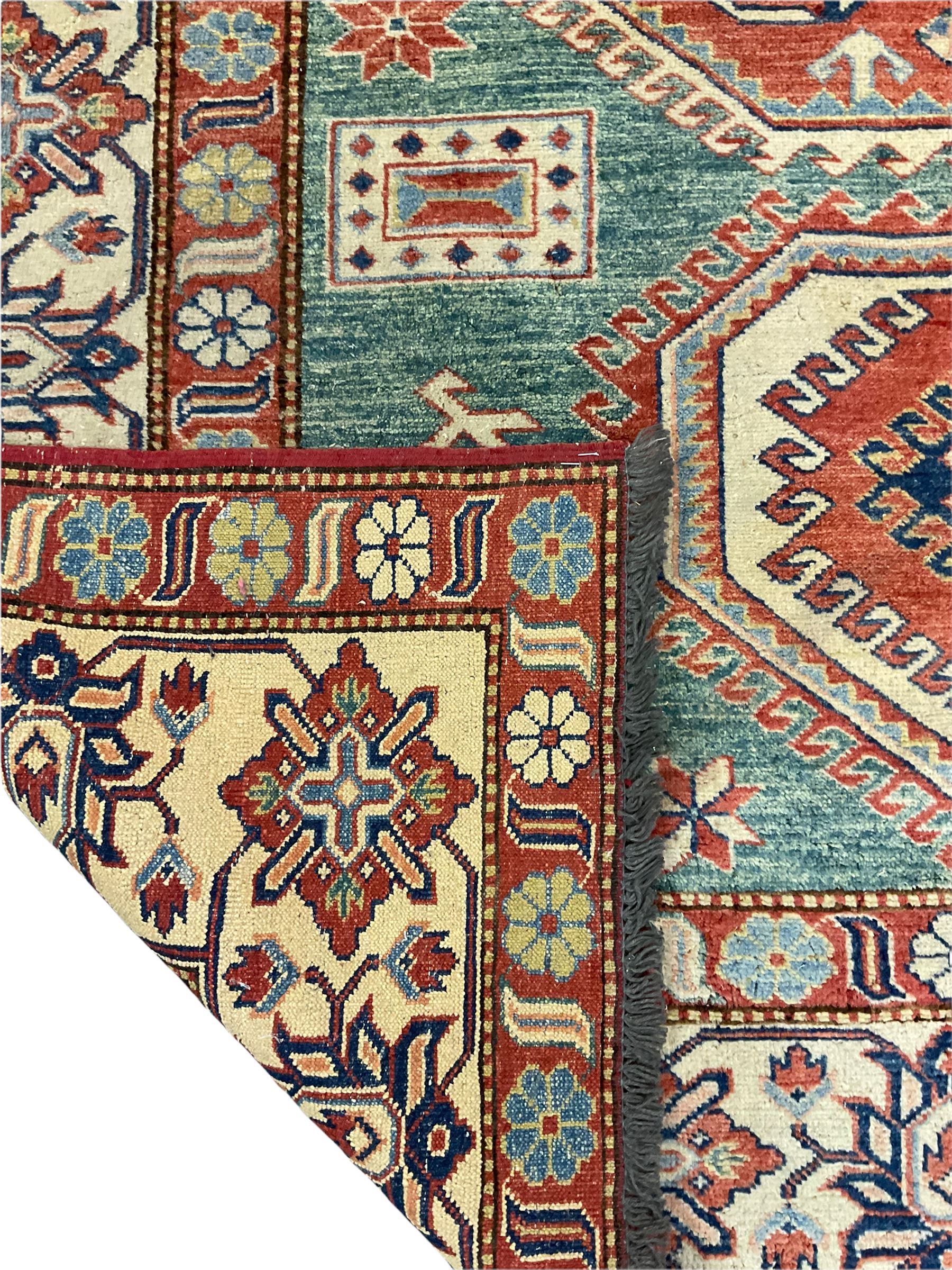Kazakh rug, pale green ground field with three part medallion, three band border decorated with stylised plant motifs