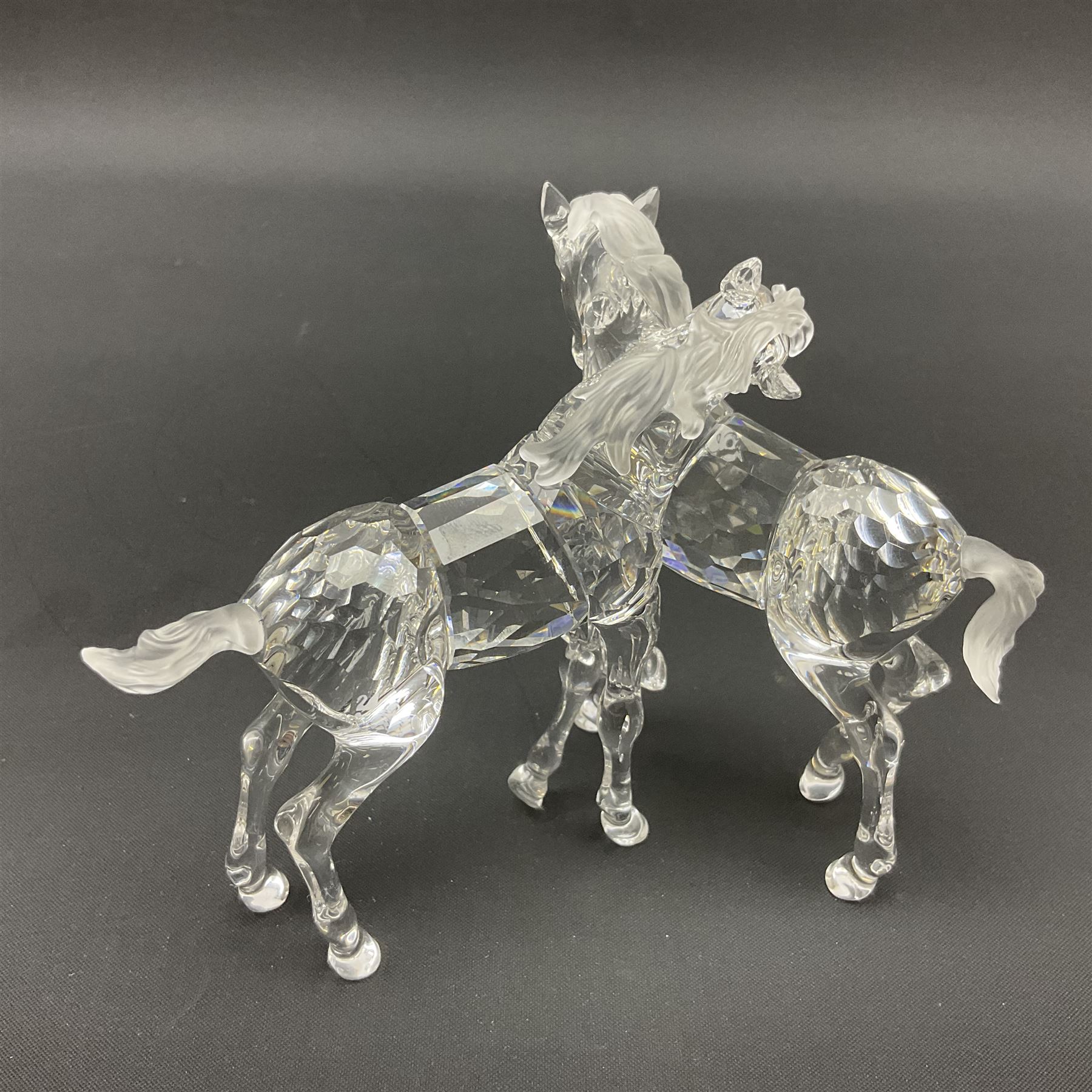 Five Swarovski Crystal horses, comprising stallion, rearing horse, pair of horses playing and Arabian stallion, each with frosted manes and tails, together with a small Swarovski Crystal galloping horse, the mane, tail and base with smoky tint