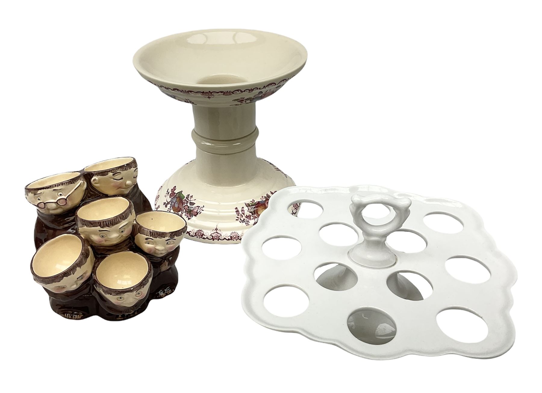 Masons Ironsone ham stand, decorated in the fruit basket pattern, together with a Weiss egg cup holder for six eggs, modelled as a group of monks, and a further egg holder, with twelve sections, marked beneath P Regout, Maastricht, in one box 