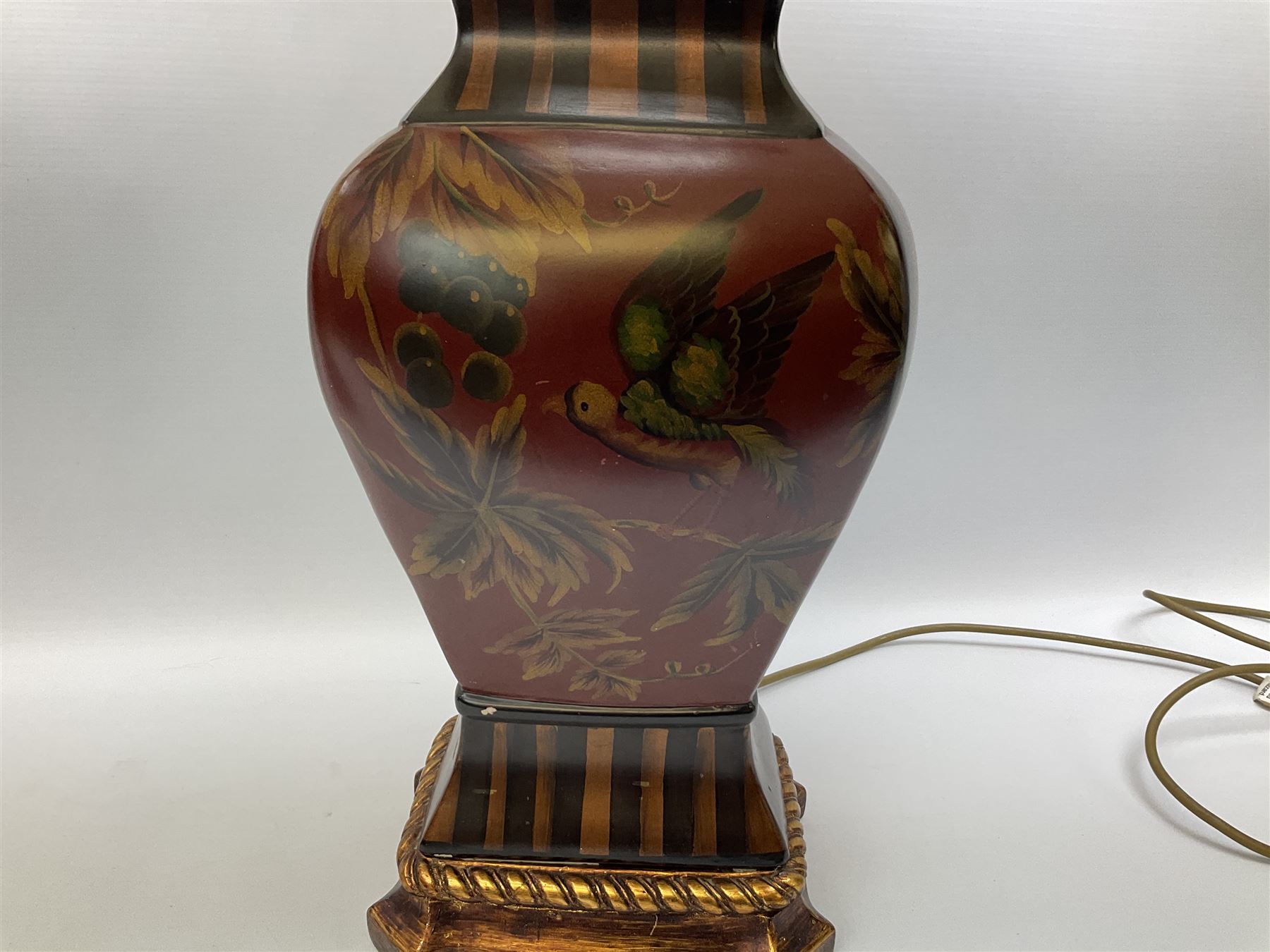Pair Oriental table lamps decorated with birds in a tree with fruit, on a red ground with a gilded base together with cream lampshades H57cm, without lampshade. 