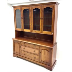 Large teak wall cabinet, projecting cornice, fitted with two double glazed doors enclosing glazed shelving, below unit is fitted with three long graduating drawers, flanked by two cupboards enclosing more shelving, raised on shaped bracket supports 
