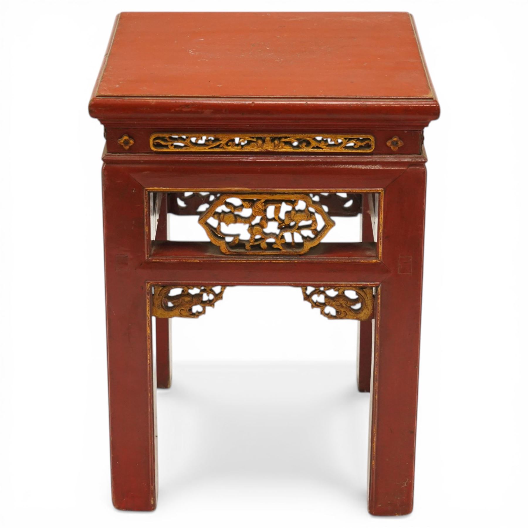 Early 20th century Chinese red lacquered occasional table, rectangular top over a pierced frieze decorated with carved giltwood floral panels and brackets, raised on moulded square tapering supports