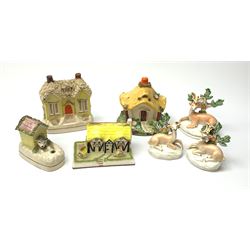 A group of Victorian and later figures, comprising Victorian Staffordshire money box in the form of a house, a Victorian Staffordshire pastille burner in the form of a house, three figures modelled as recumbent deer before trees, Staffordshire style model of a dog emerging from a kennel upon pen holder base, and Coalport pastille burned in the form of a house. (7). 