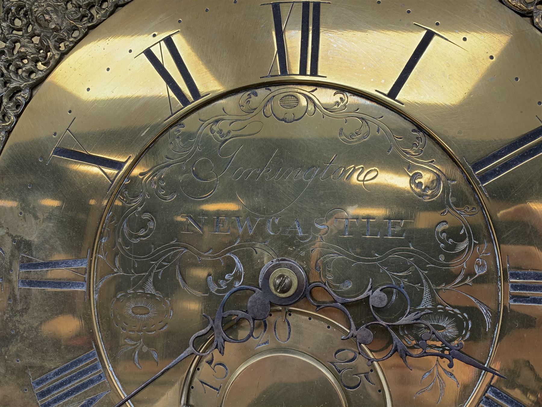 Early 19th century oak longcase clock, projecting cornice over frieze painted with scrolls, square glazed door enclosed by plain pilasters, square brass dial with ornate cast metal spandrels, Roman chapter ring and false subsidiary date aperture, engraved decoration and inscribed 'Torkington, Newcastle', 30-hour movement striking on bell