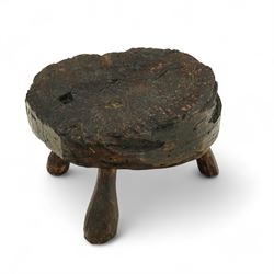 Rustic bog oak stool of oval form with a single solid section with a deeply patinated and textured surface, raised on three tapered stick legs, possibly Irish 