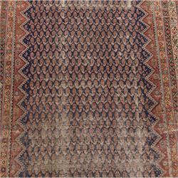 West Persian Kurdish vintage carpet, indigo field decorated with an all-over repeating boteh design arranged in diagonal rows framed by angular spandrels and enclosed by multiple geometric borders in a palette of indigo blue, madder red, soft green and ivory