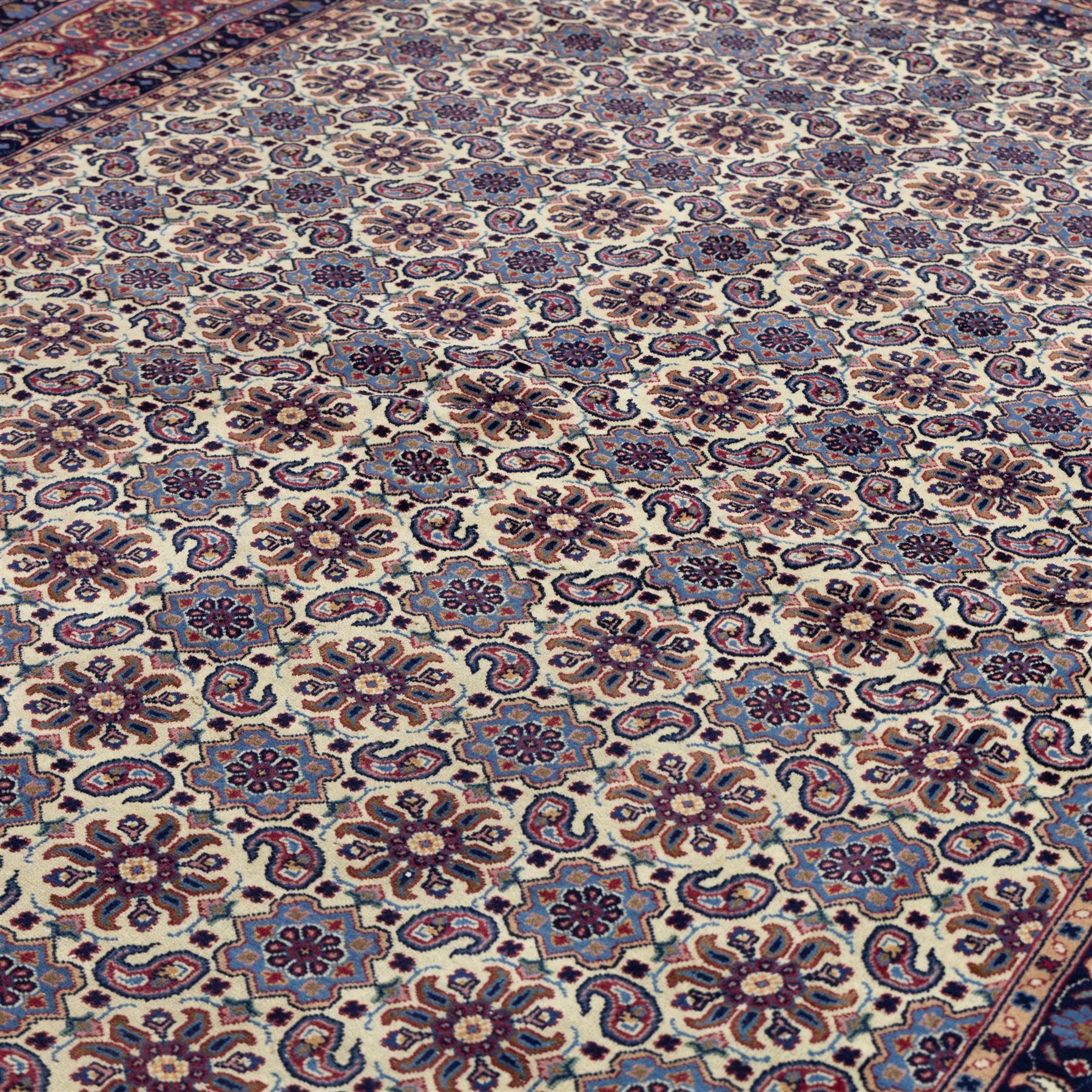 North West Persian Tabriz hand-knotted carpet, ivory field densely decorated with an all-over Herati style (Mahi) lattice composed of stylized rosettes and scrolling leaves, enclosed by a broad madder-red border of palmette and floral vine design, between navy guard stripes, cotton fringe ends 