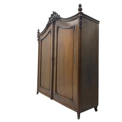 Early 20th century Italian walnut armoire wardrobe, the pierced and scrolling pediment carved with acanthus leaf detail, flanked by two scrolling cartouche with matching corbels below, the two panelled doors with applied carved rinceaux slips, with a central spiral turned upright, enclosing single shelf and hanging rail, raised on scroll feet
